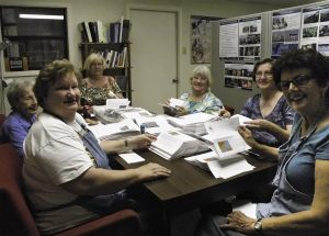 smiling volunteers at a table help prepare mailings
