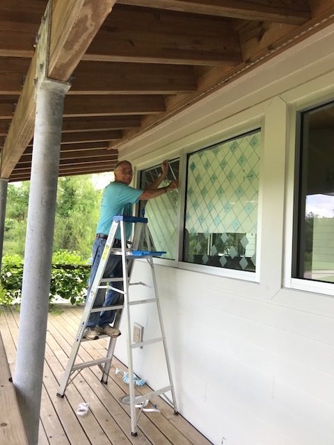 man placing bird tape on windows