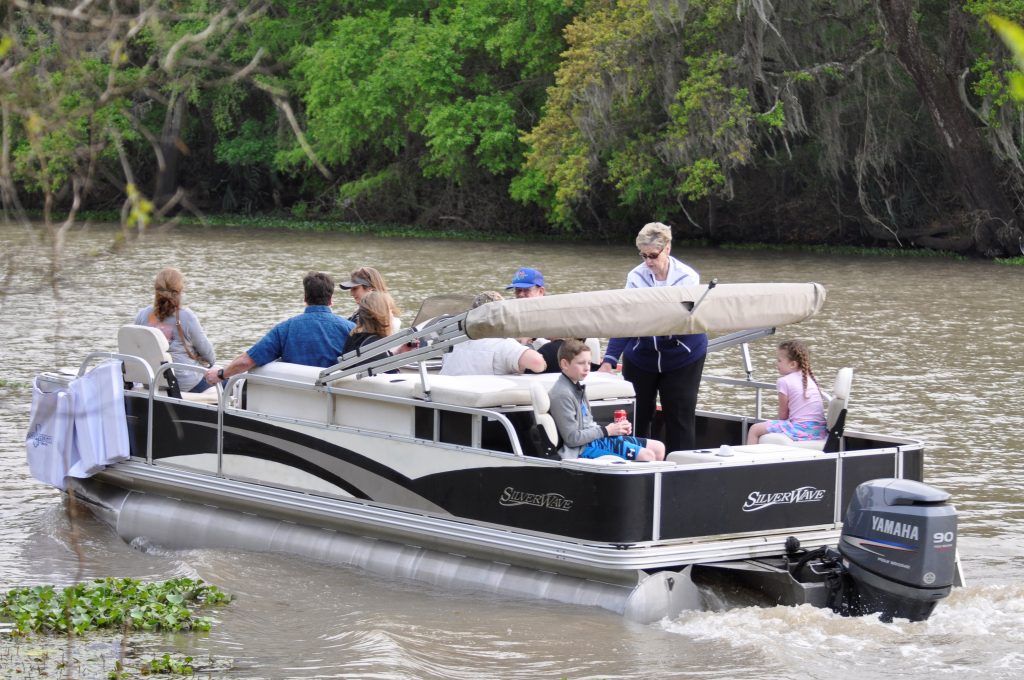people enjoy a pontoon boat ride on the bayou